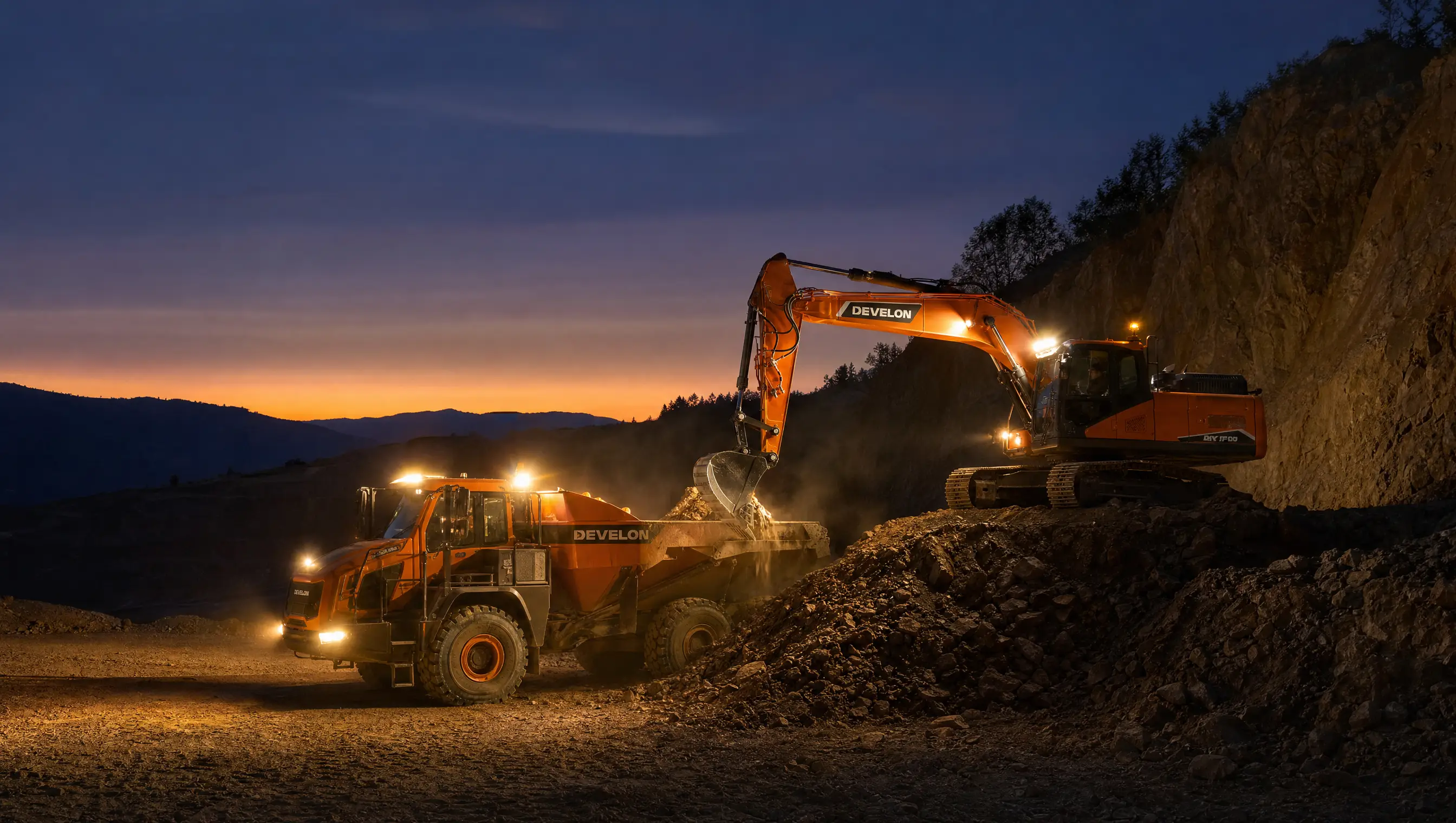A DEVELON excavator loading a dump truck at dusk with work lights on